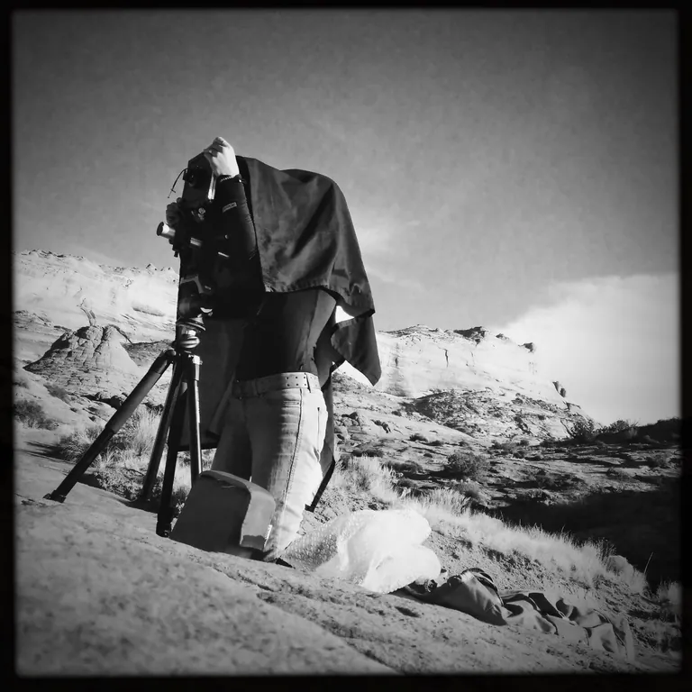 Nicholette Jean working under a dark cloth with a large-format camera in the desert