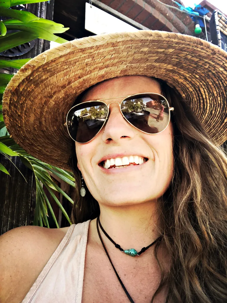 Nicholette Jean, founder of NJ Media Works, in an oversized straw hat and aviator sunglasses